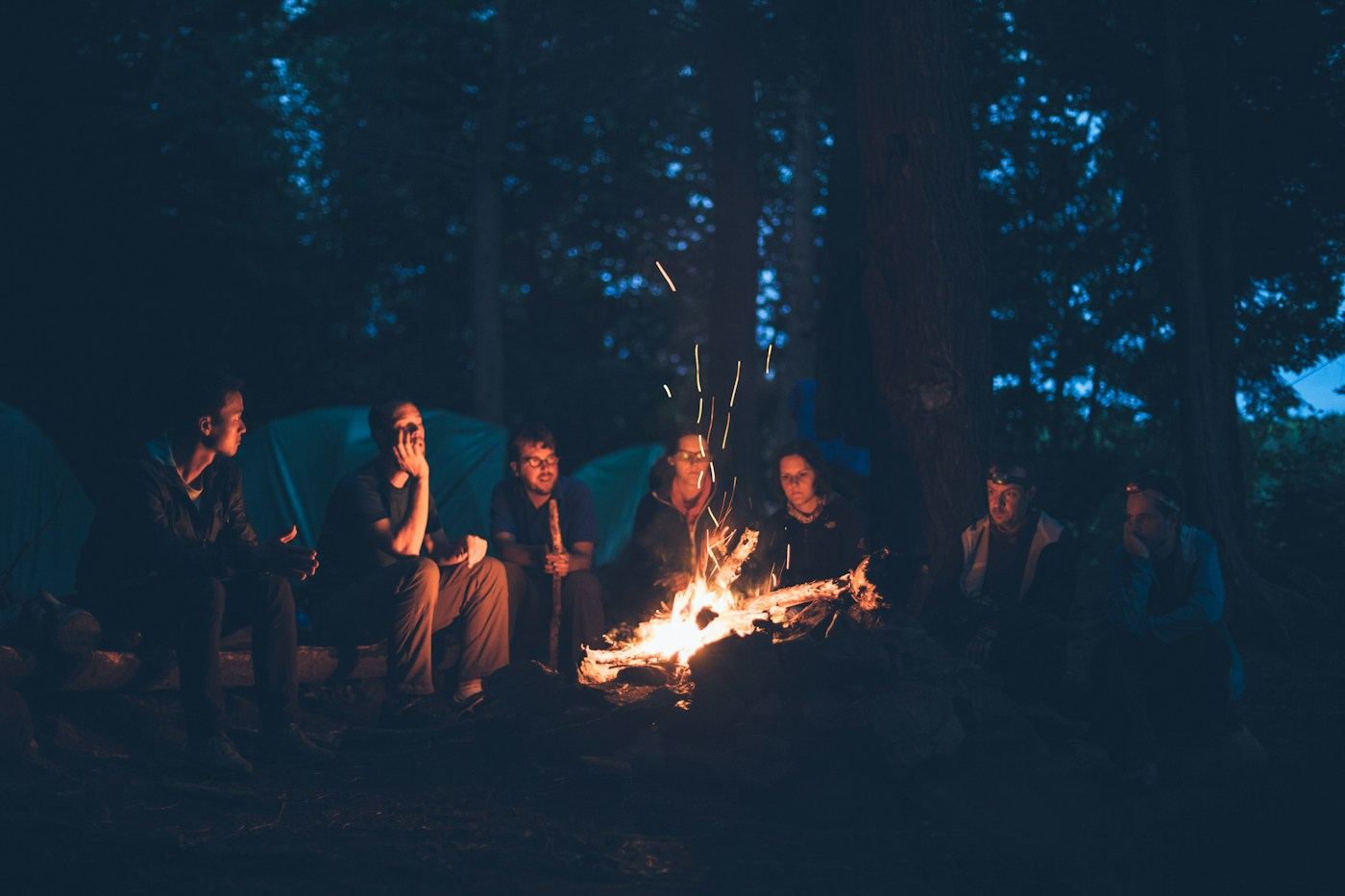 Friends gathered around a campfire at night