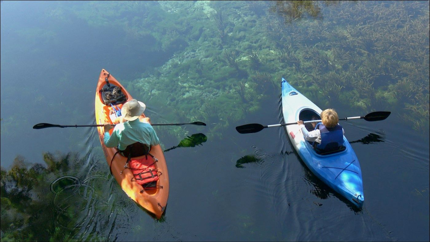 Two people paddling kayaks on calm water