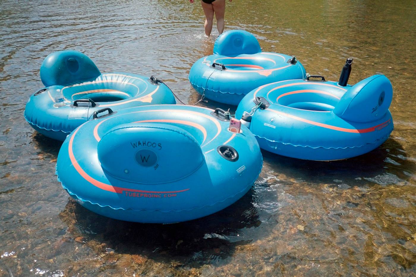 Blue inner tubes floating on a clear river