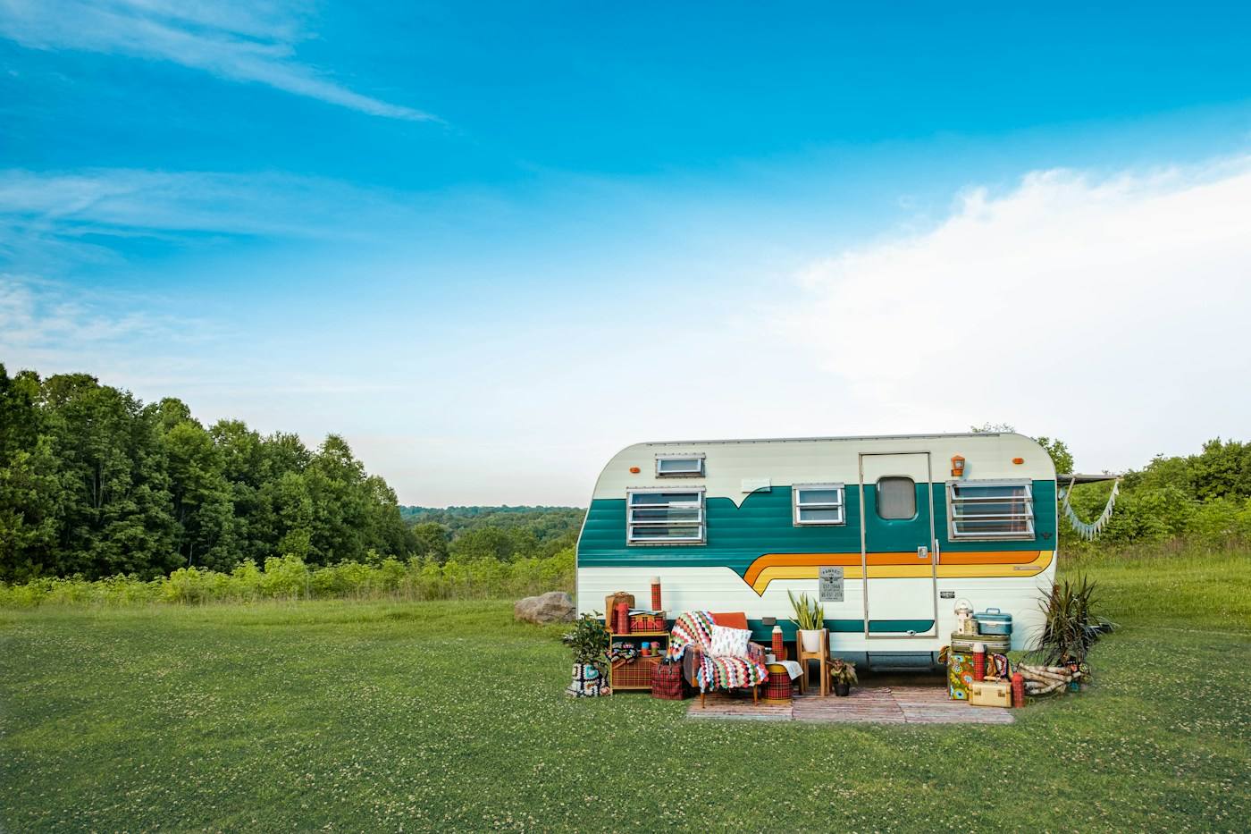 Vintage travel trailer on a green field under blue sky